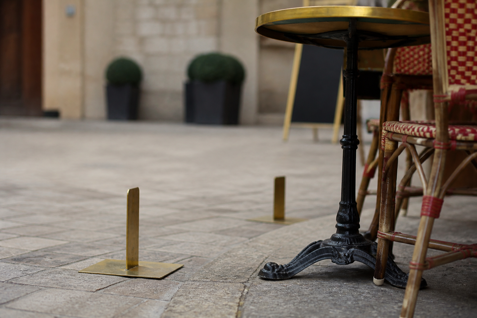 Détail d’une terrasse de café sur une place historique, avec mobilier extérieur et sol pavé évoquant l’occupation du domaine public.